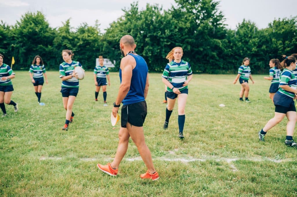 Coach leading a youth rugby practice session in the park
